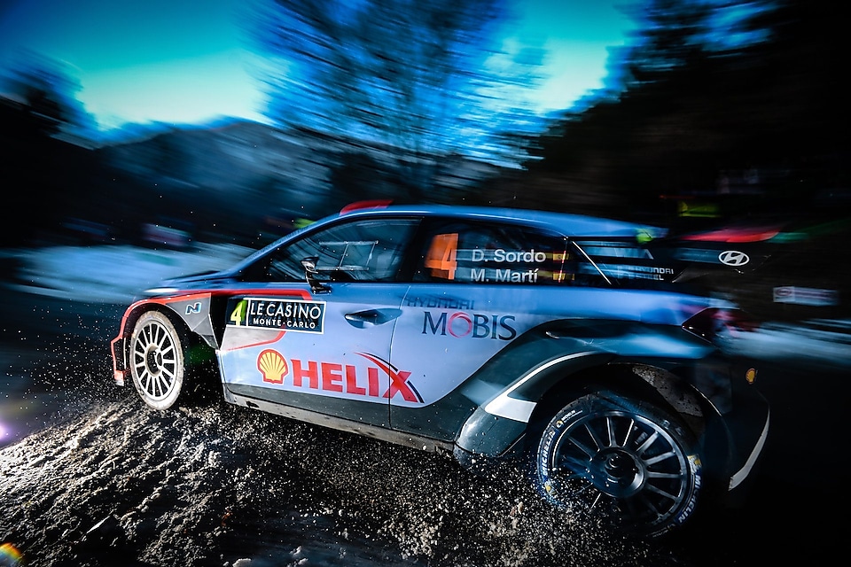 Rally-auto rijdt snel in het ochtendlicht in het wereldkampioenschap rally